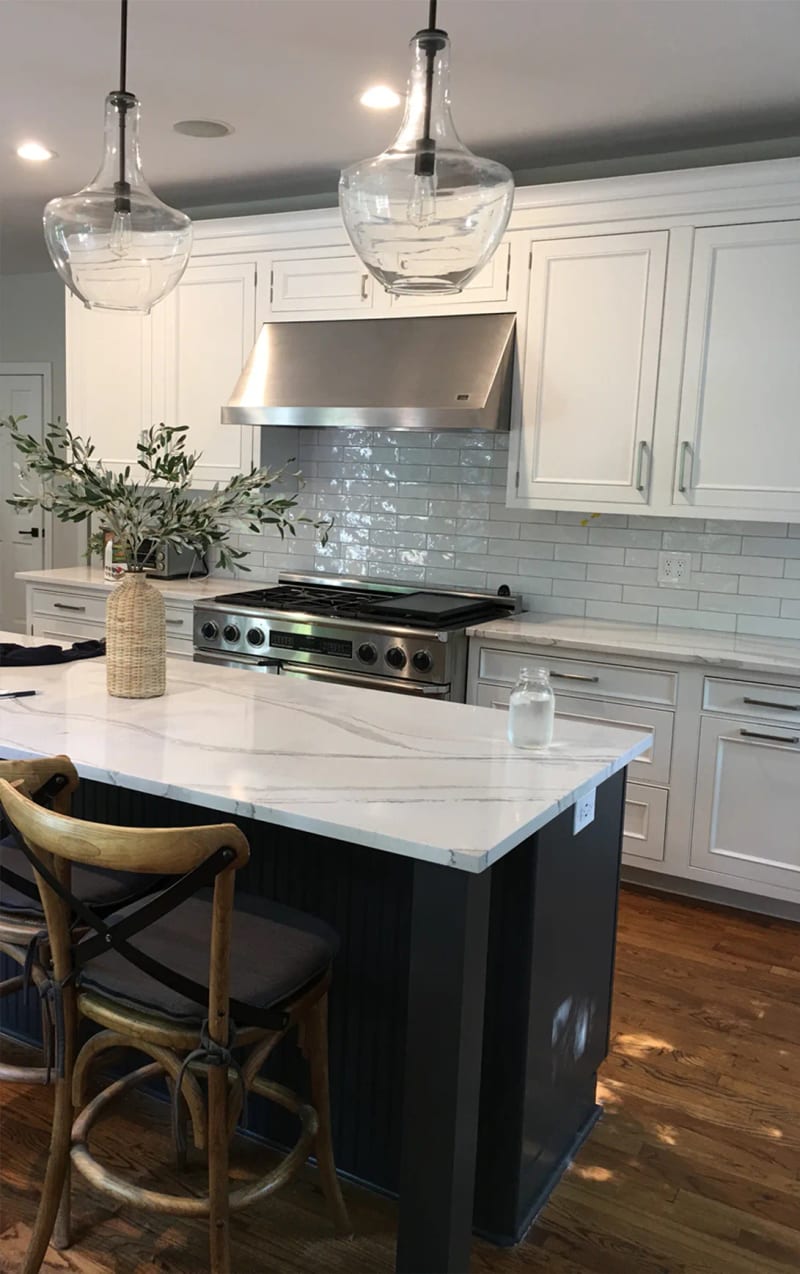 Lake Bluff kitchen with white cabinets, a navy island and stainless range hood