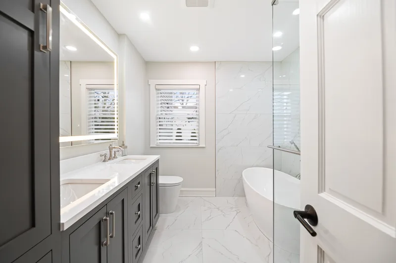 Lake Bluff bathroom remodel by Delta - Bathroom and Kitchen Remodeling: charcoal shaker double vanity, marble-look walls, and freestanding tub