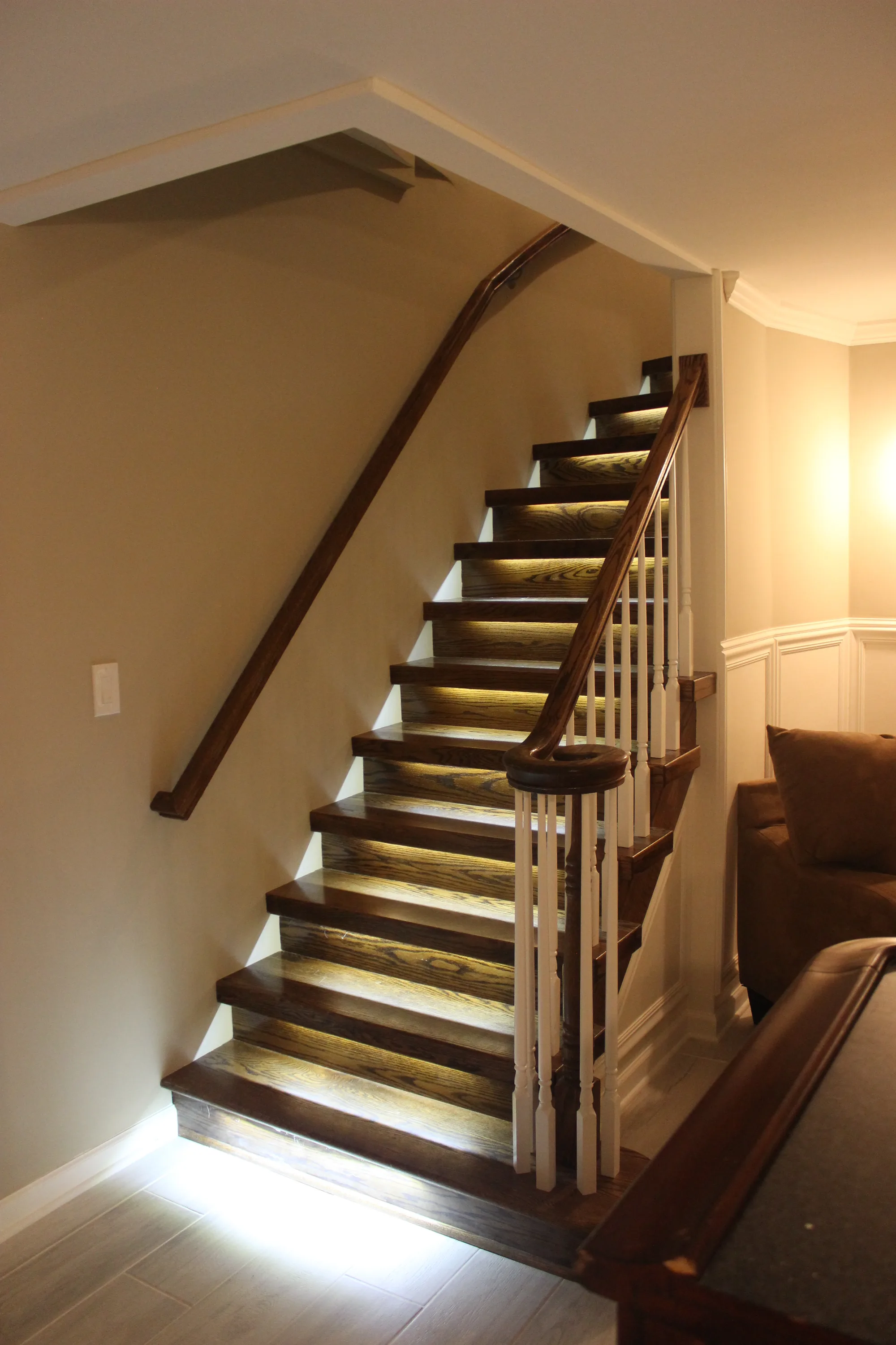 Highland Park basement by Delta: refinished oak staircase with traditional turned spindle railing, mahogany handrail, integrated LED step lighting