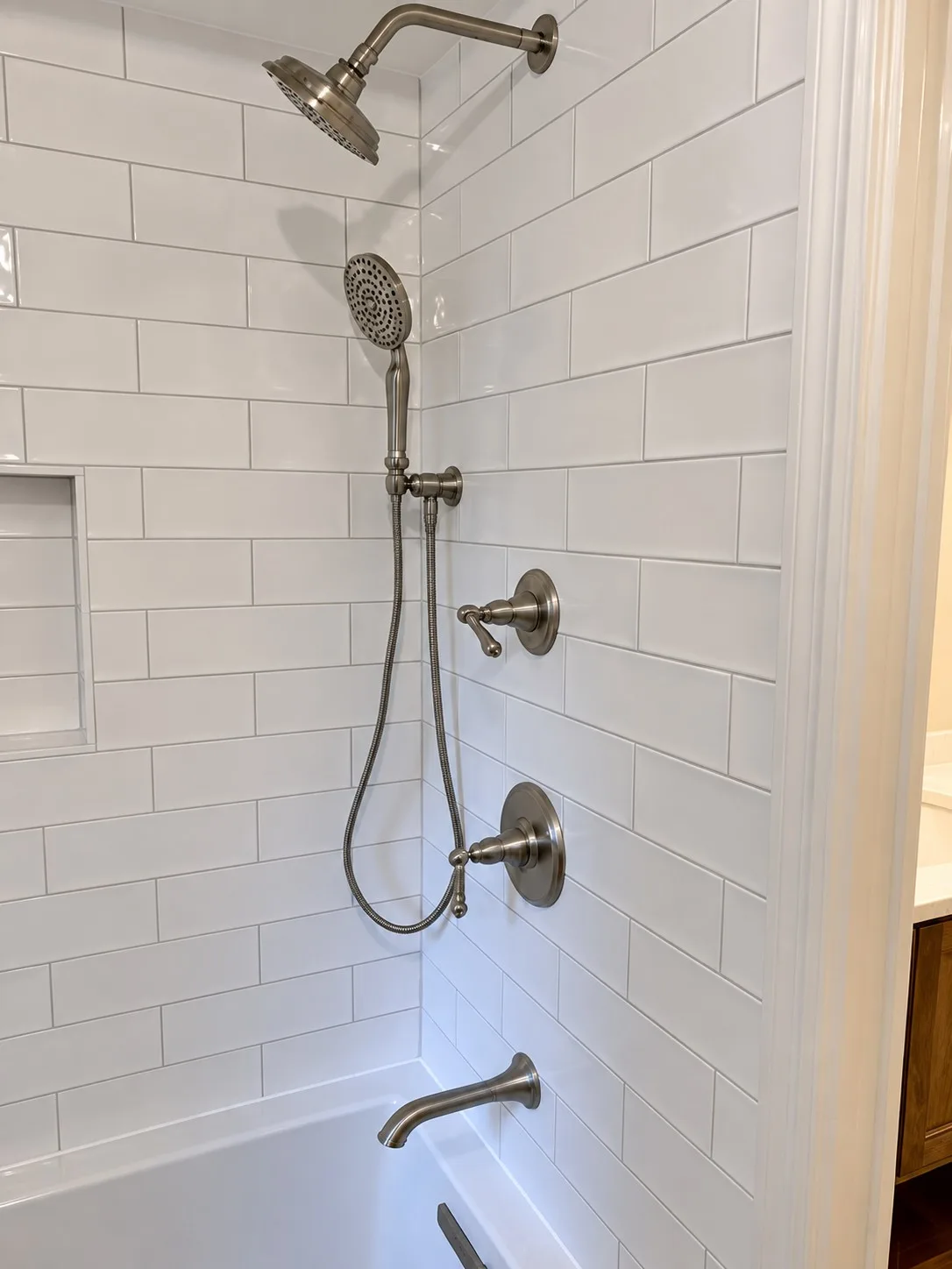 White subway tile tub and shower with rain showerhead, handheld shower and recessed niche in a Libertyville bathroom remodel