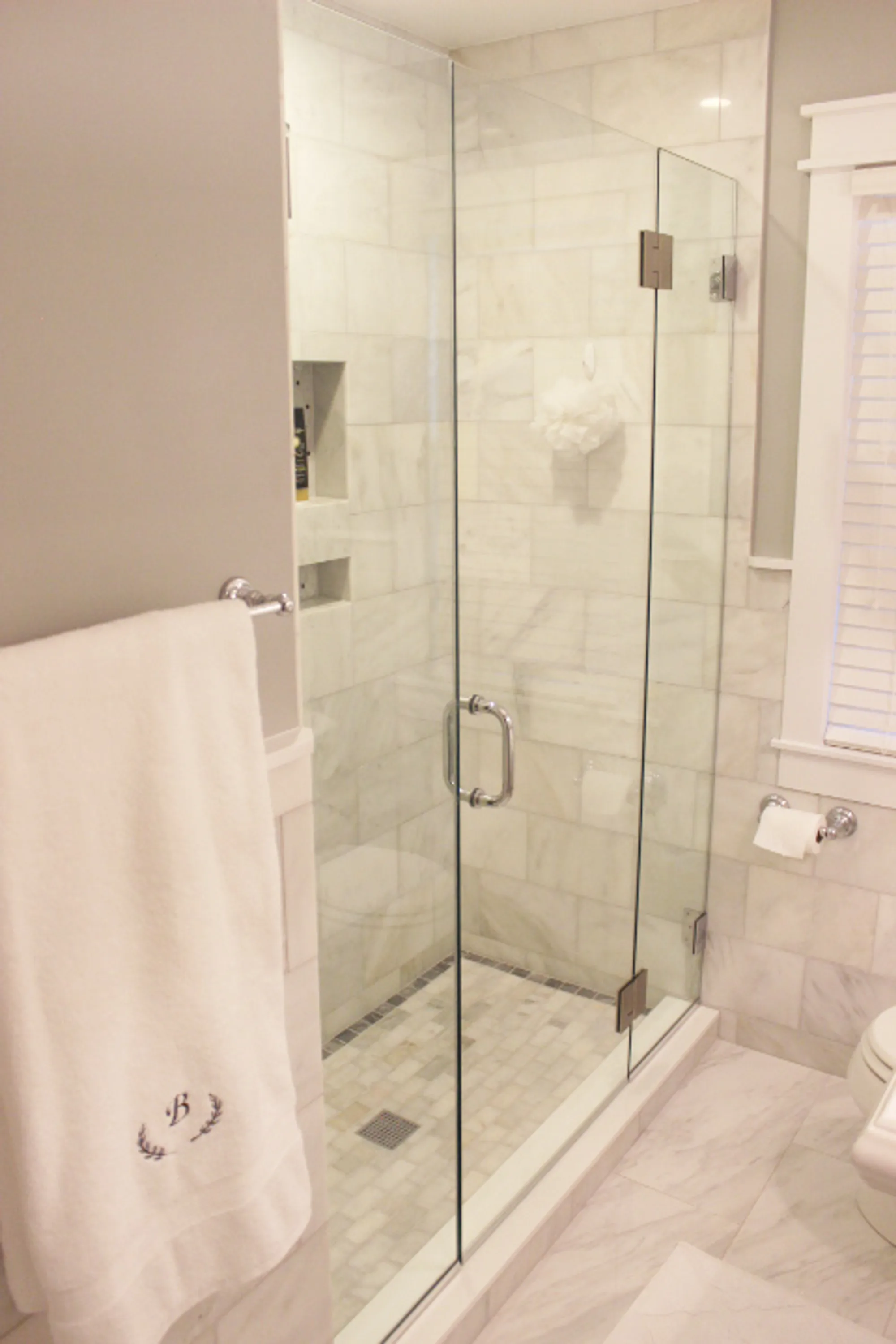 Northbrook bathroom by Delta: carrara marble subway walk-in shower with basket-weave floor, marble herringbone outer floor, chrome hardware