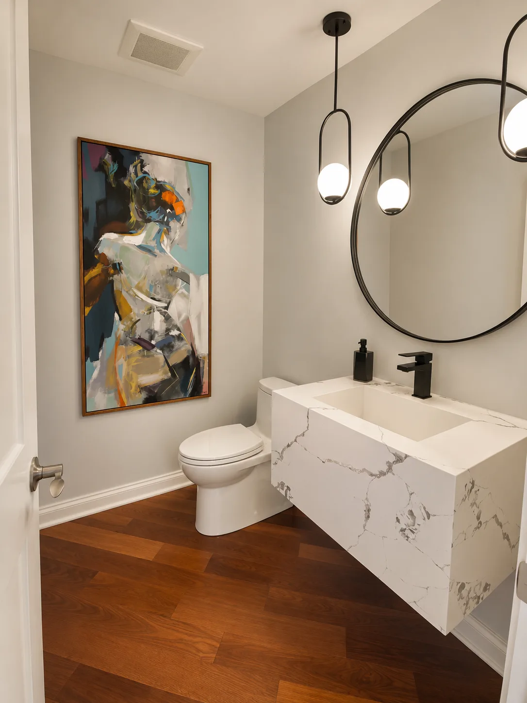 Completed Lake Bluff powder room with a floating marble waterfall vanity and round black mirror