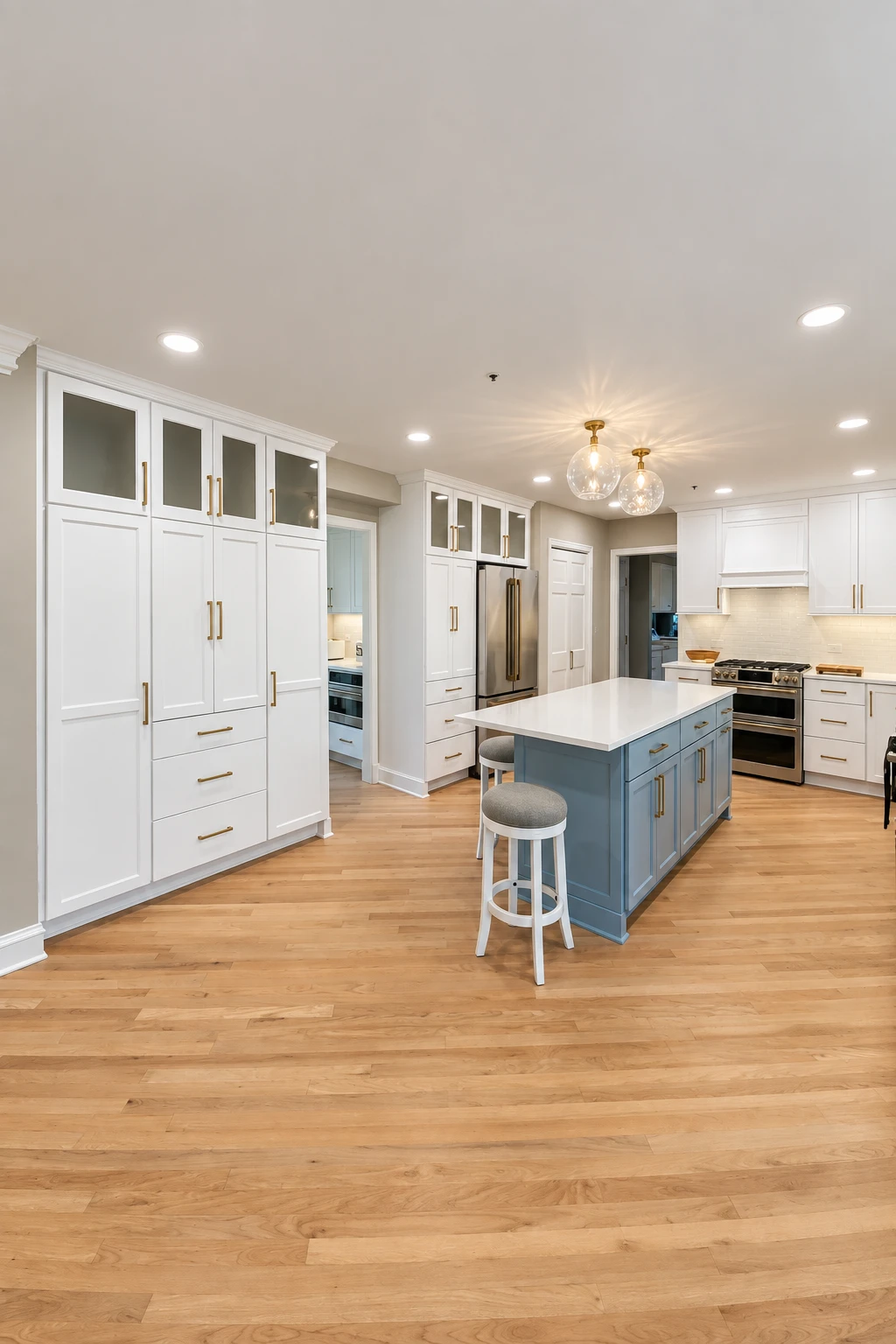 Blue-gray kitchen island with brass pulls and a double-oven range under a white hood in a Long Grove kitchen