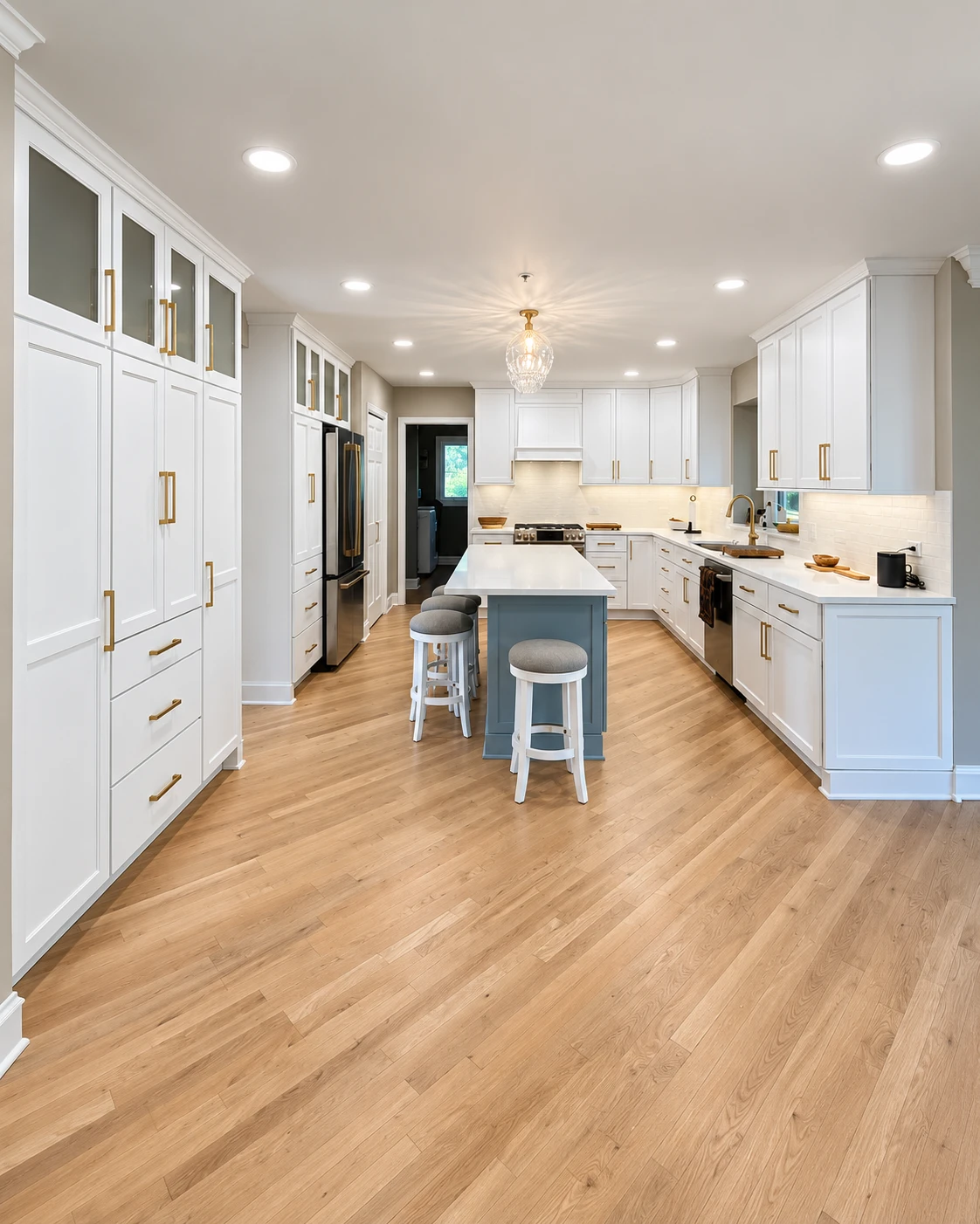 Long Grove kitchen remodel with white shaker cabinets, a blue-gray island with seating, brass hardware and light hardwood floors