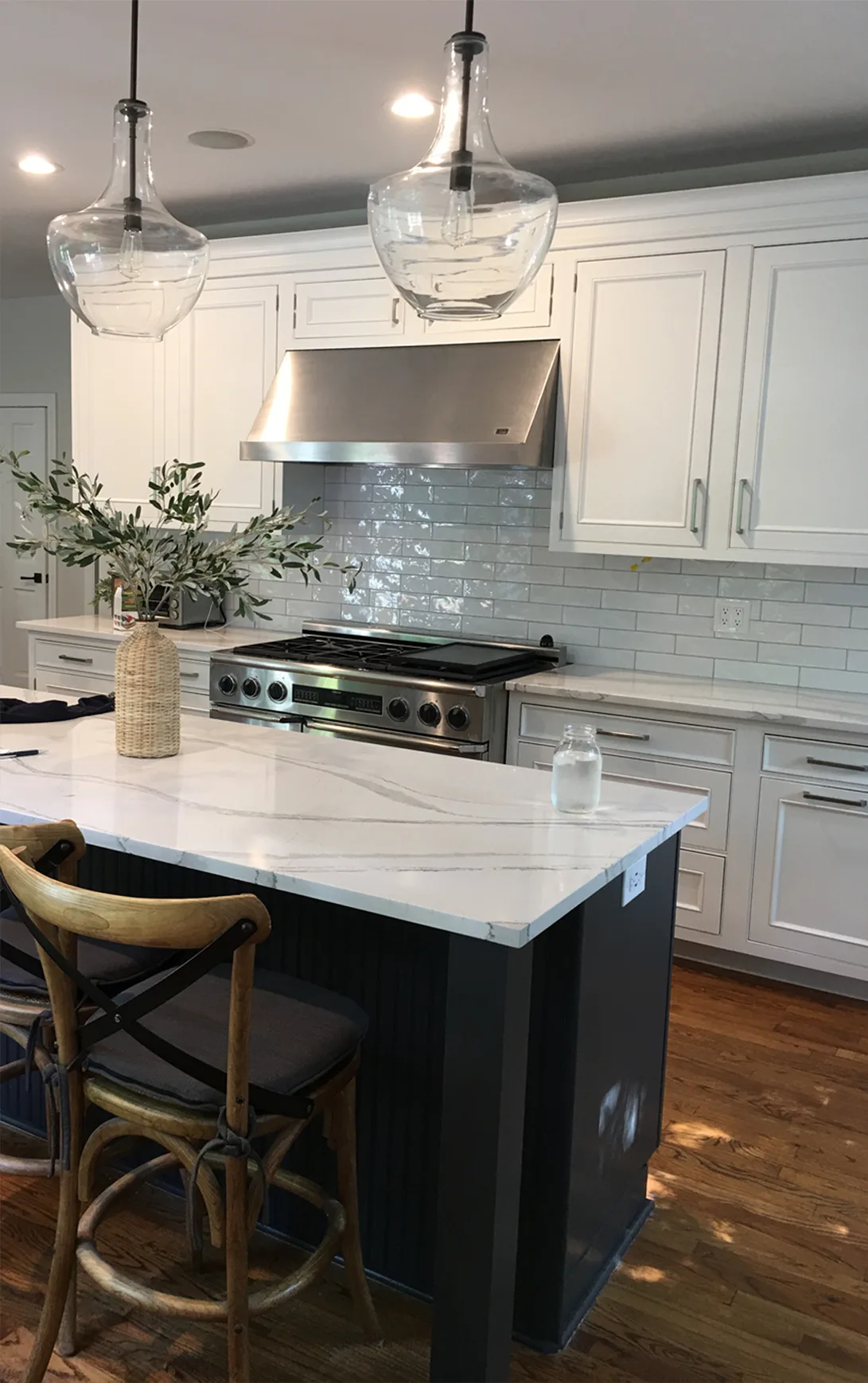 Lake Bluff kitchen by Delta: white inset cabinetry, fluted navy island with calacatta quartz waterfall, zellige subway backsplash, professional gas range, demijohn pendants