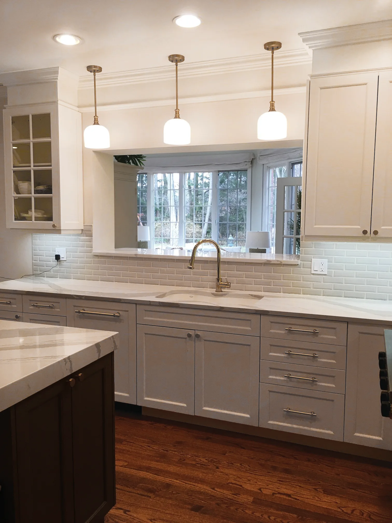 Lake Forest kitchen: marble waterfall island with brass pulls and saddle counter stools