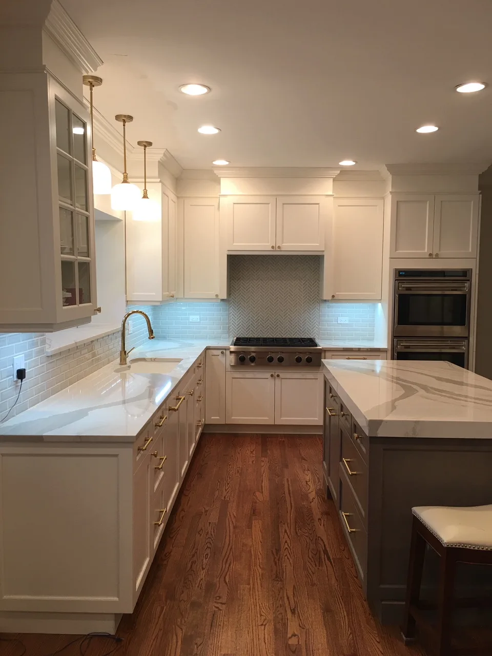 Lake Forest kitchen: herringbone marble range wall behind stainless gas cooktop and double wall ovens