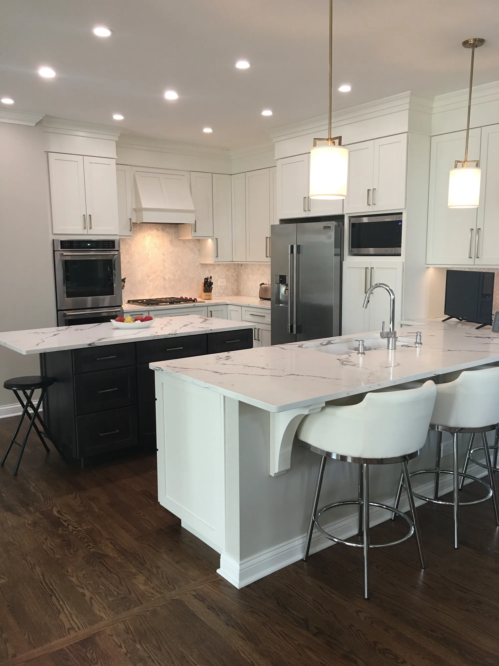 Lake Forest estate kitchen by Delta: two-island layout with white shaker cabinetry, espresso shaker prep island, calacatta quartz counters, herringbone marble backsplash