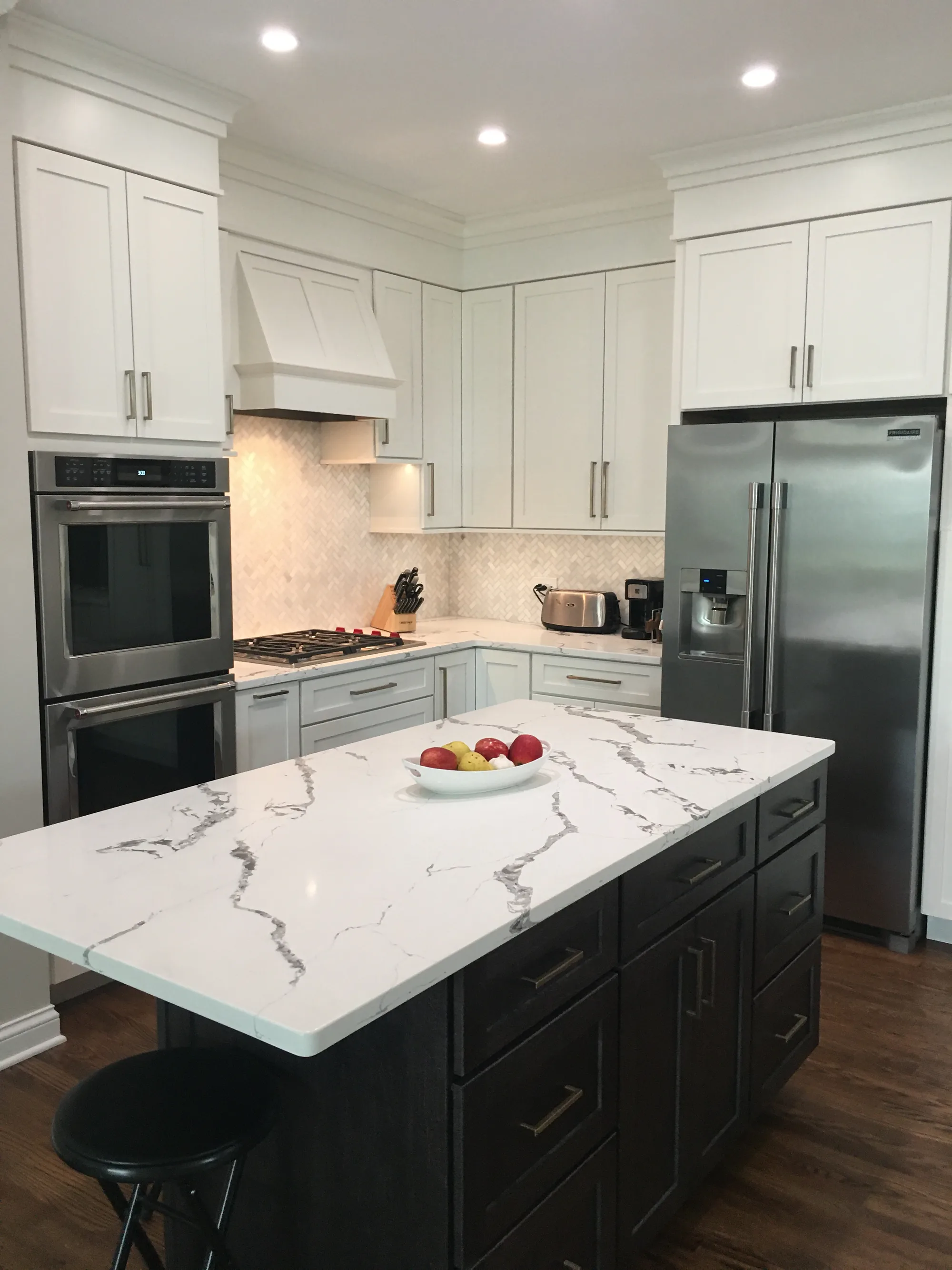 Lake Forest two-island kitchen: white shaker cabinetry with herringbone marble backsplash and stainless double wall ovens