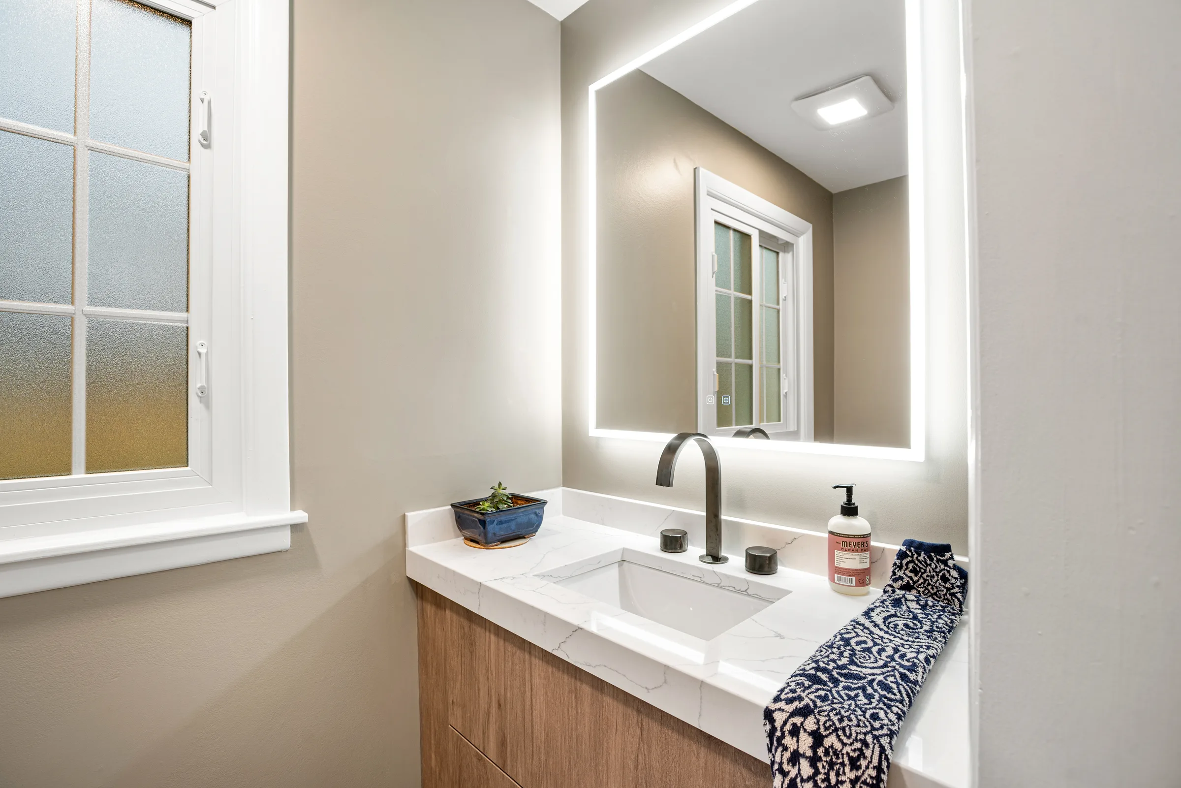 Lake Forest powder room remodel: wood slab vanity with quartz counter, backlit mirror, and matte black faucet