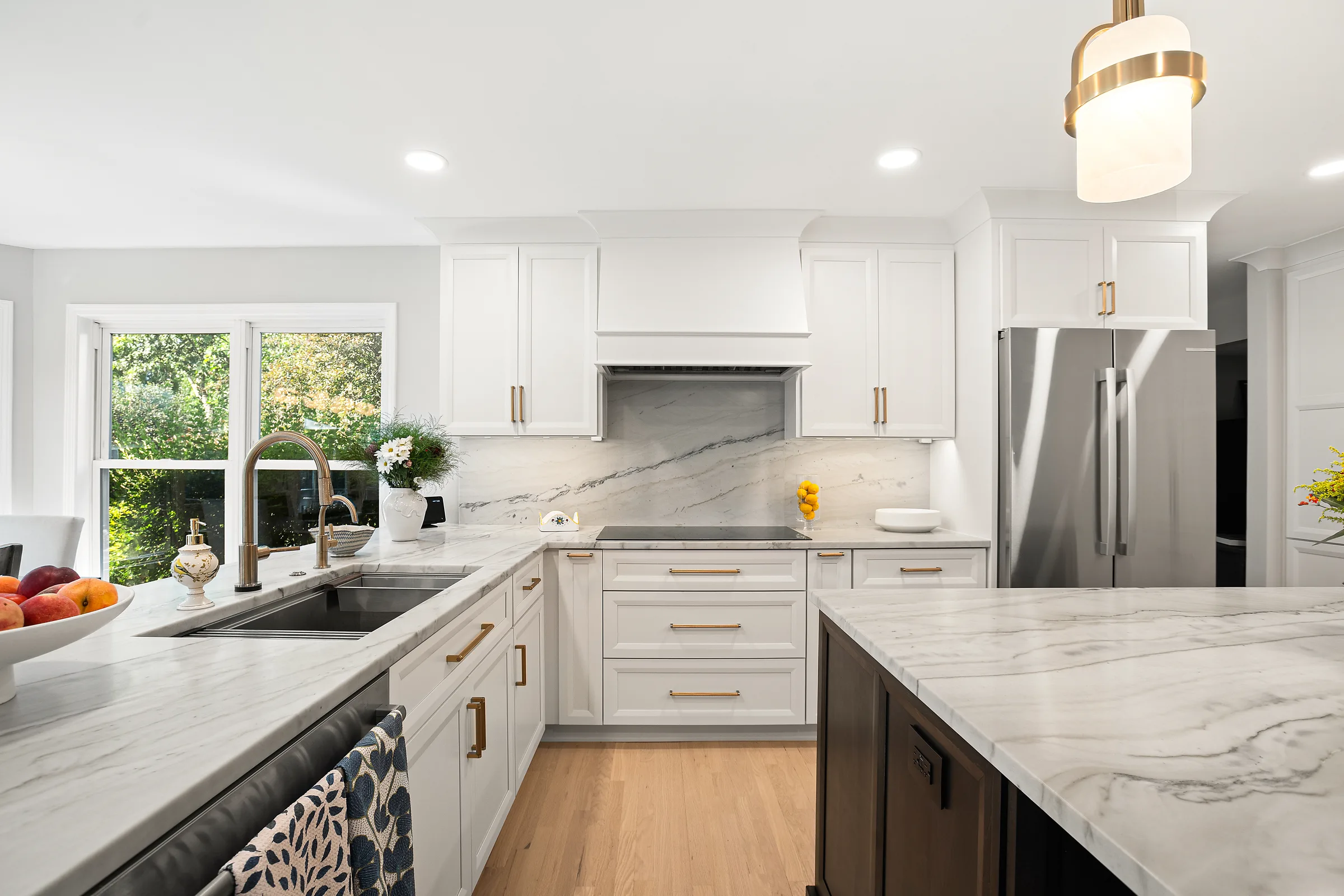 Glenview kitchen remodel by Delta Remodels: marble island with quilted counter stools and brass pendants