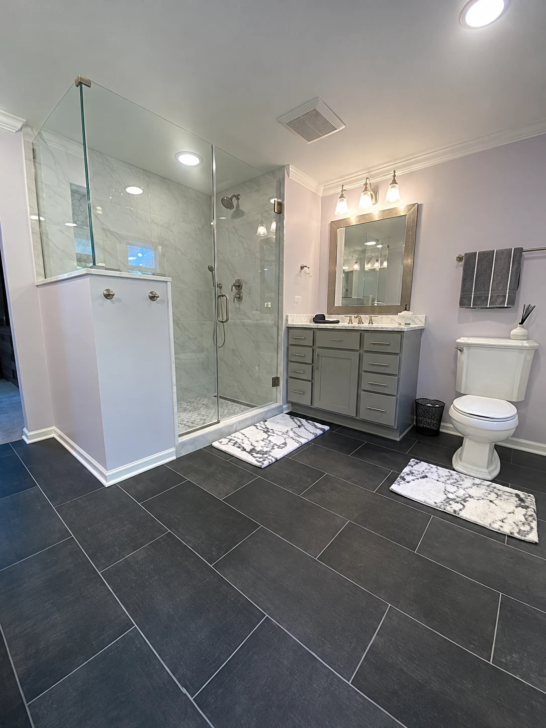 Expanded primary bathroom remodel in Lincolnshire, Illinois, with a glass walk-in shower, gray vanity and charcoal floor tile