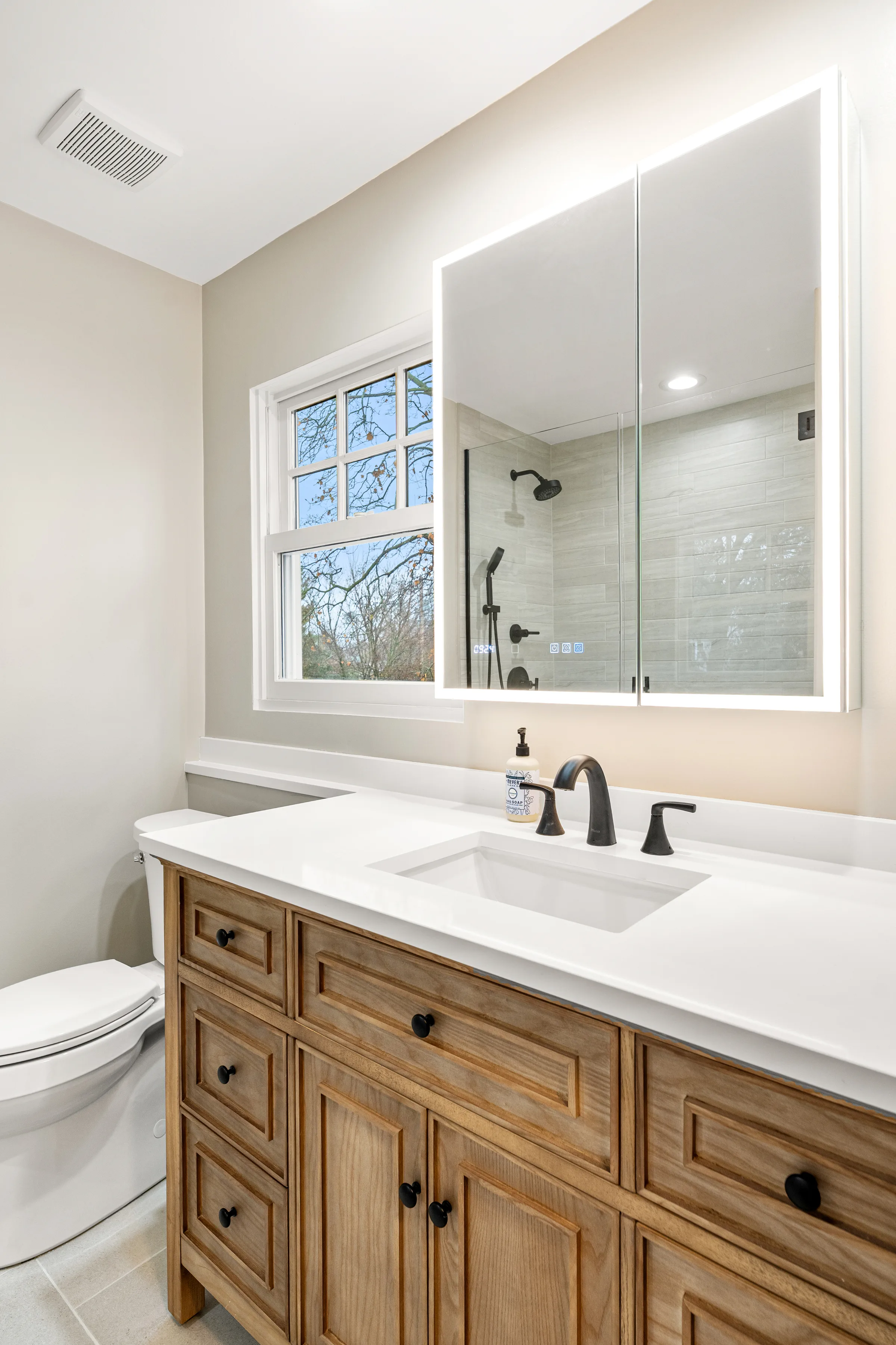 Northbrook bathroom remodel: mirrored medicine cabinet over warm-wood vanity