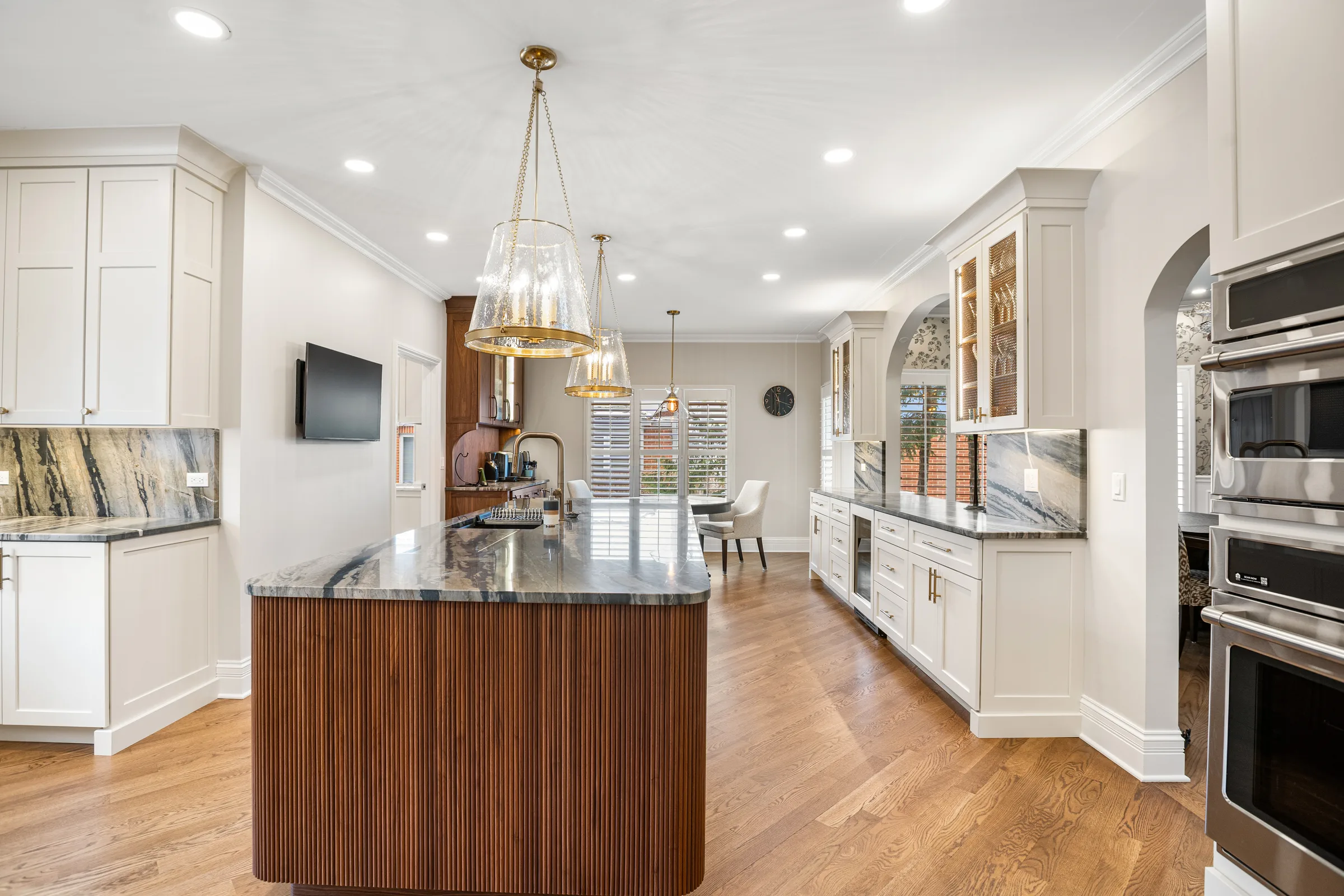 Lake Forest kitchen remodel: white perimeter cabinetry with walnut fluted island and brass pendants