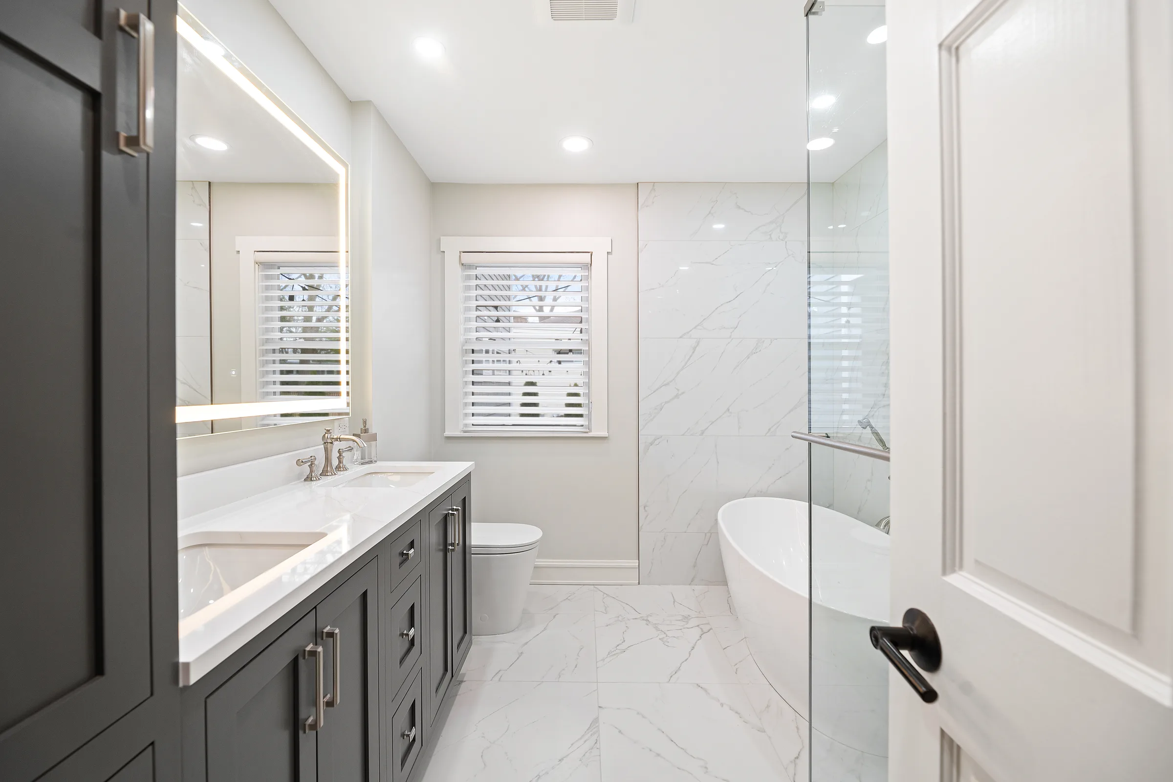 Lake Bluff bathroom remodel: charcoal shaker vanity with marble-look walls and freestanding tub