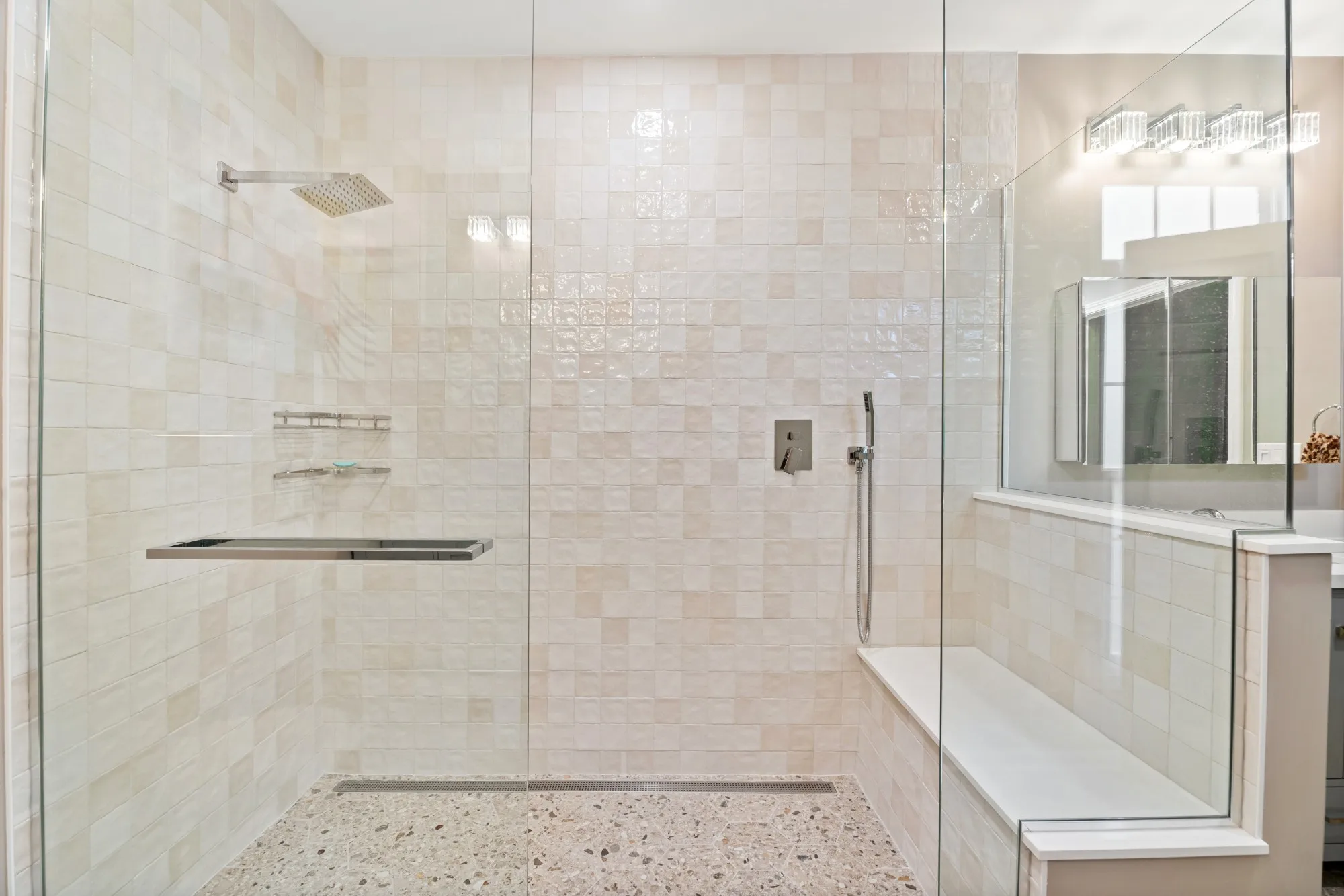 Frameless glass walk-in shower with glossy cream square tile, a square rain head and a long towel bar