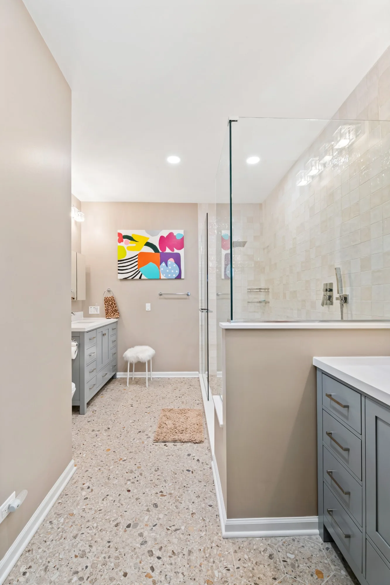 Primary bathroom seen from the doorway with a gray vanity, glass shower and terrazzo-style floor