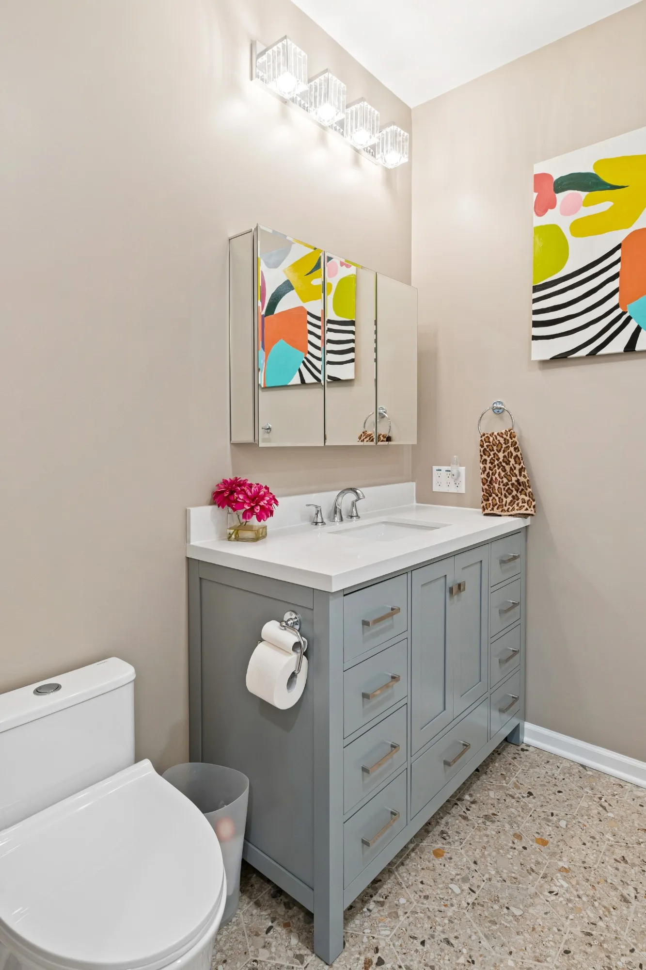 Gray vanity with brushed pulls on a terrazzo-style hexagon tile floor
