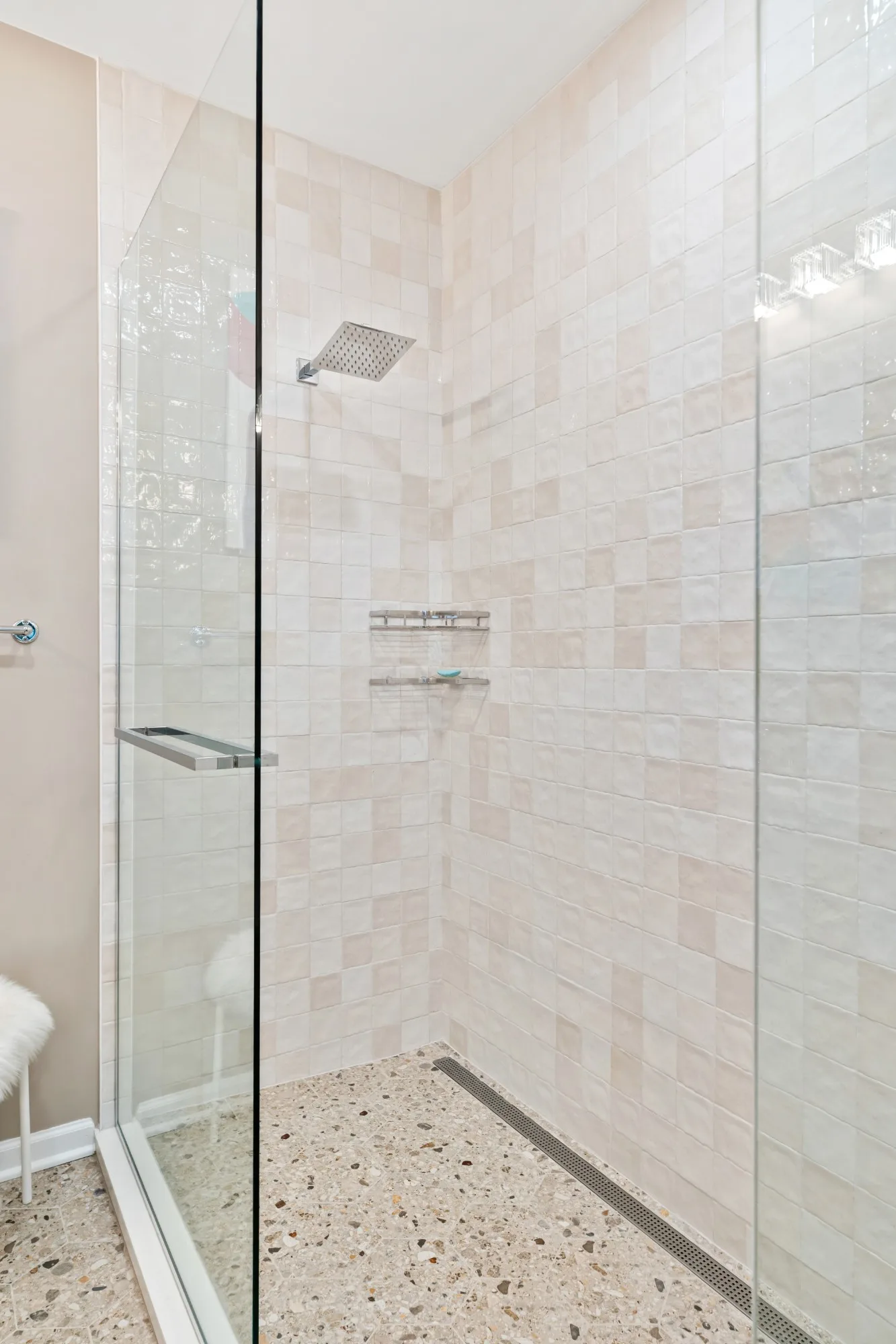 Terrazzo-style hexagon floor tile running into the walk-in shower beside a linear drain
