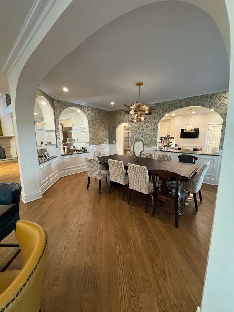 Dining room with arched display niches, botanical wallpaper, wainscoting, oak floors and a sculptural chandelier