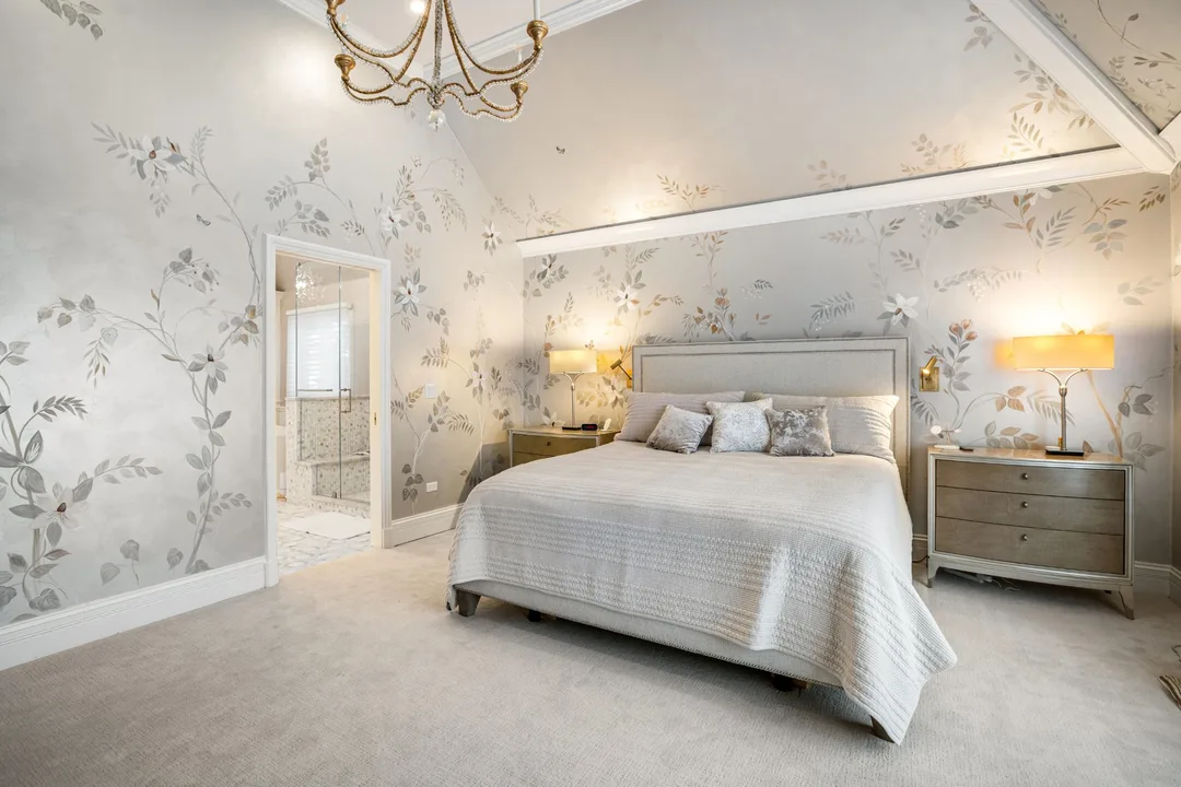 Primary bedroom with hand-painted mural walls and a gilded chandelier, with the doorway open to the marble ensuite bathroom