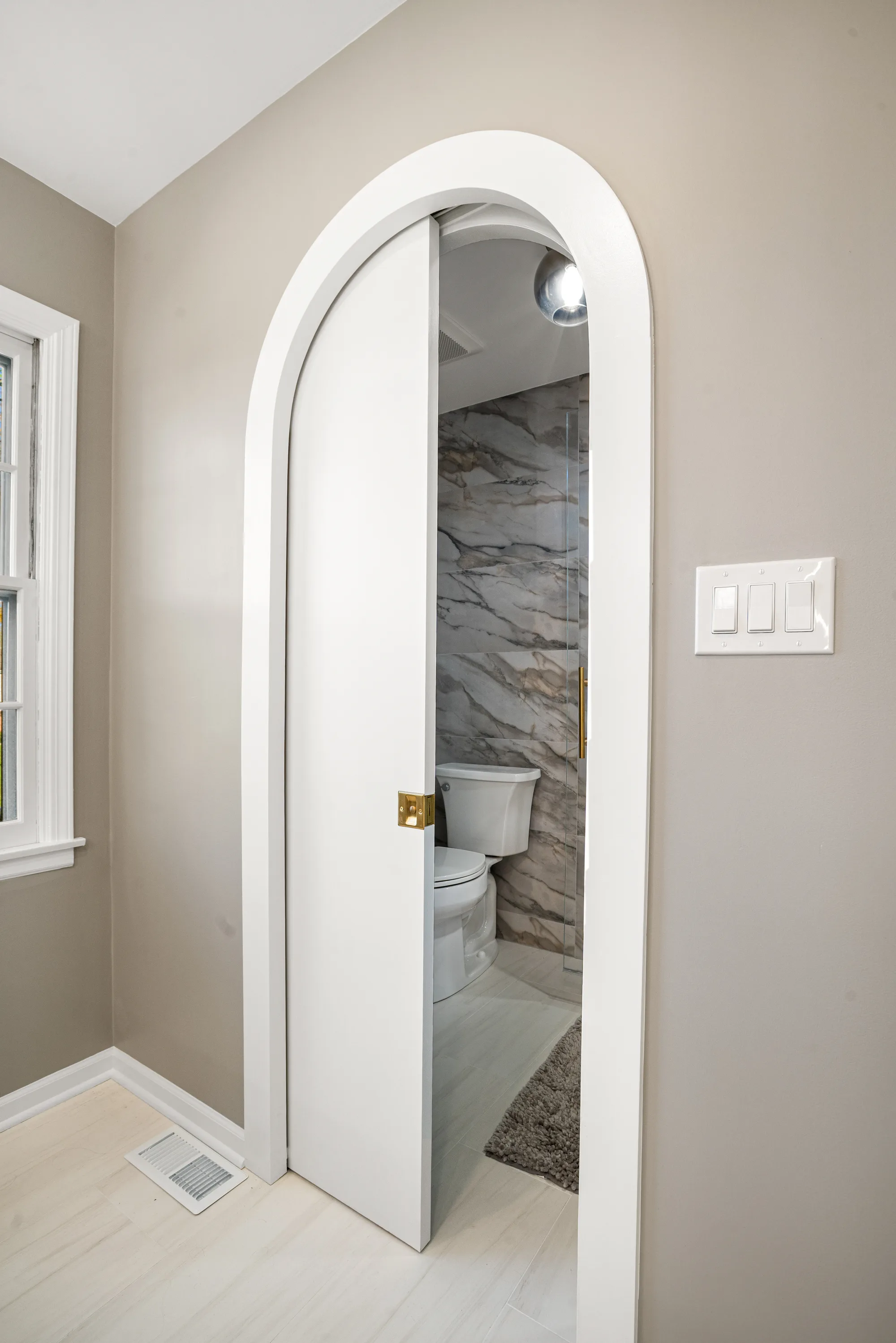 Wilson Road bathroom Lake Forest: vertical fluted glass brass sconces flanking backlit mirror